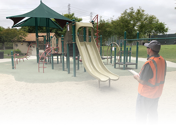 Worker with orange vest surveys playground construction